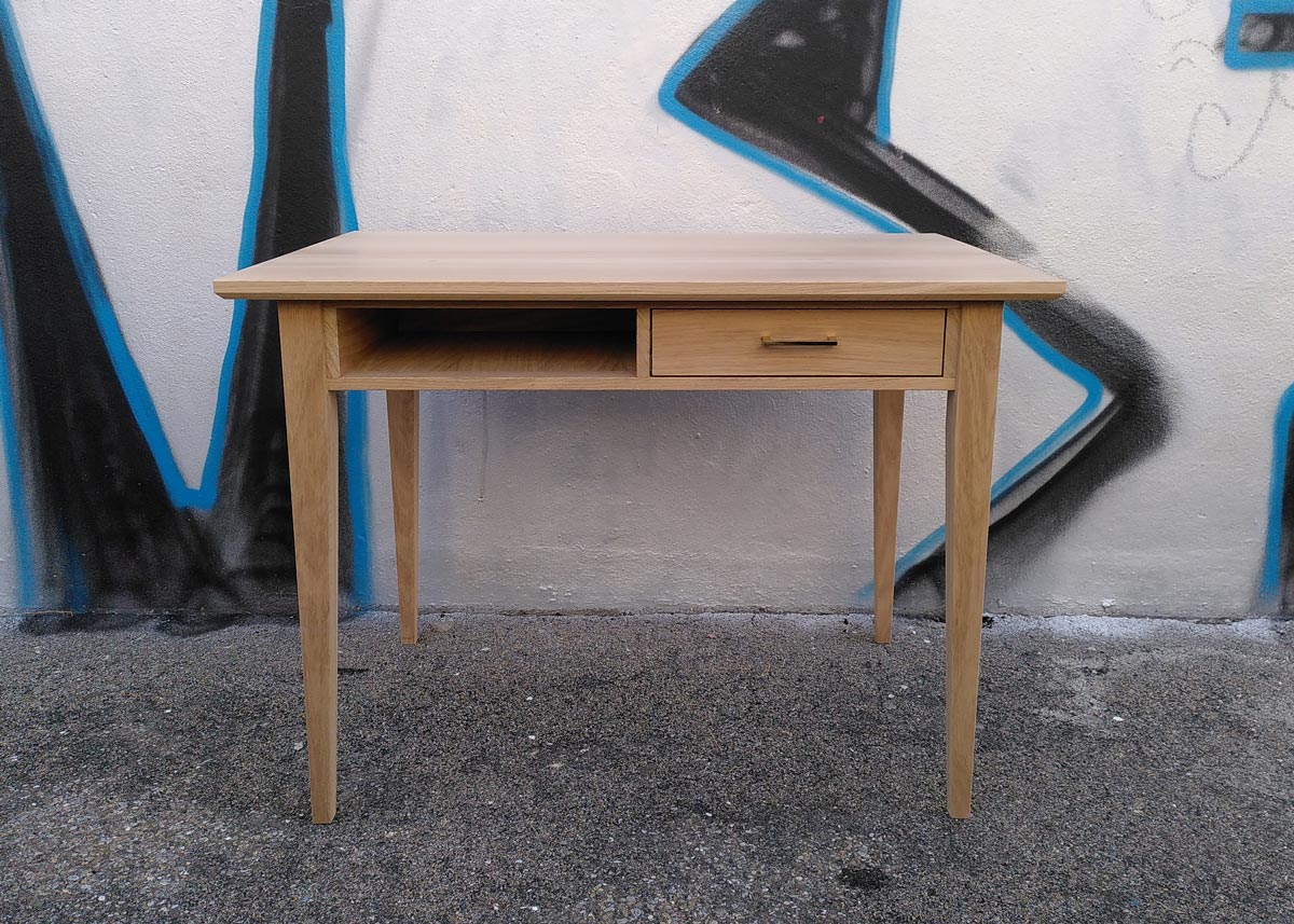 Tisch mit Schublade in Frontalansicht vor einer Graffitiwand